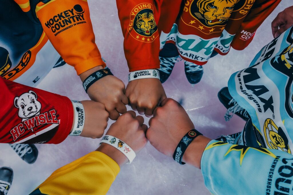 Fäuste von Kindern in den Trikots der fünf Hockey-Country-Clubs mit Hockey-Country-Armbändern